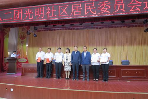 北屯市副市长、师市民政局局长蔡震，民政局副局长郭庆，182团党委副书记、团长秦子郎为新当选的社区居委会委员颁发当选证书并合影。