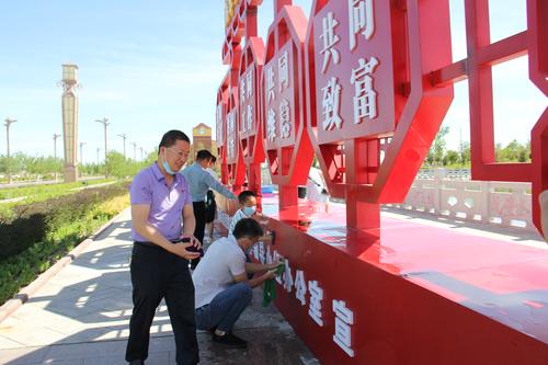 党员干部正在对民族团结宣传标识牌进行清洁