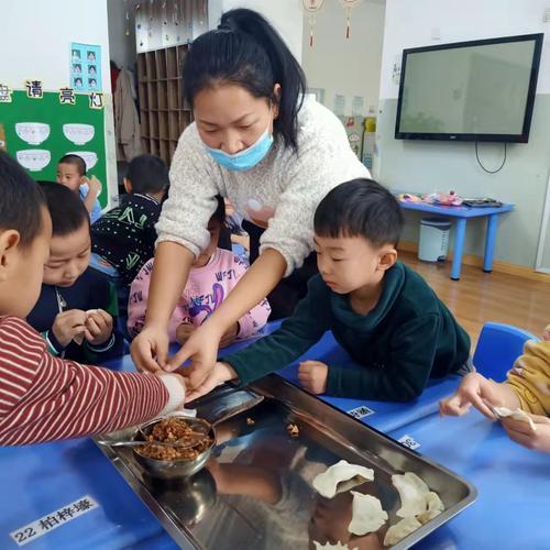 大班幼儿正在老师的帮助下包饺子