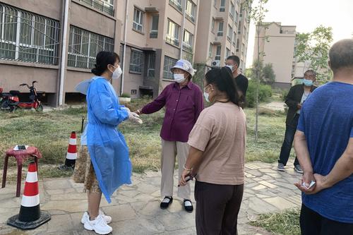 图3 十师北屯市党委网信办红细胞志愿者（左一），在北屯市一小区引导核酸检测居民排队检测。艾丽摄