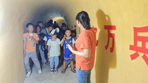 7月17日，一八六团妇联同志（右一）领着少年儿童在龙珠山地道参观  李凯悦摄影