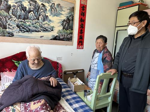 图为工作人员为退休人员蒲爷爷进行上门认证