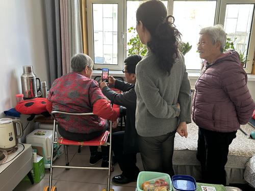 图为工作人员贾永帮助老人使用电子社保卡小程序完成认证