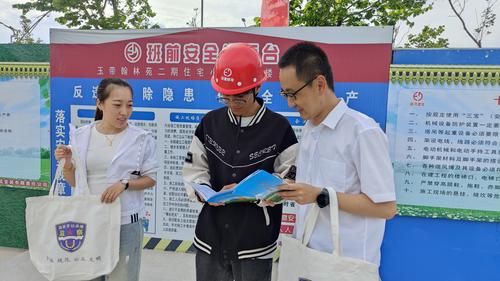 图为工作人员在工地现场为工人讲述工伤保险的重要性