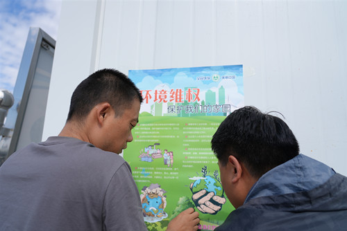 1工作人员在企业厂区张贴宣传海报。谢国庆摄