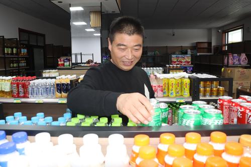 图为：11月21日，吴占东正在装饰一新即将开业的超市内将商品摆放柜架。谢国庆摄