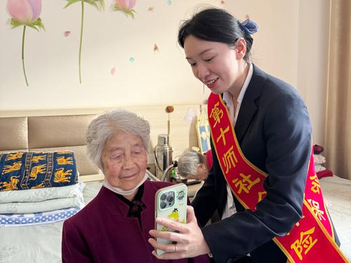 图为业务人员（右）手把手指导老人完成本年度养老待遇资格认证