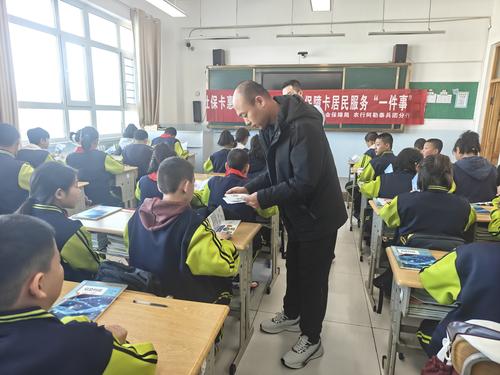 图为十师188团社保所工作人员向学生发放社保宣传册