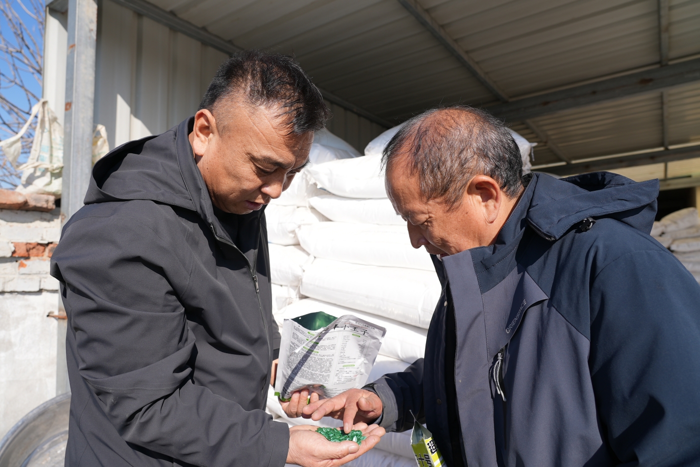 七连书记王瑞锋（左）走访入户职工吕后涛（右）家中查看种子储备情况。谢国庆摄