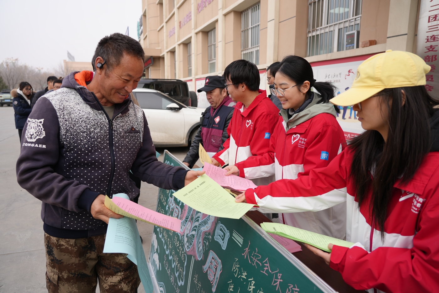 一八二团新时代文明实践所大学生志愿服务队队员在向过往群众发放宣传手册。谢国庆摄